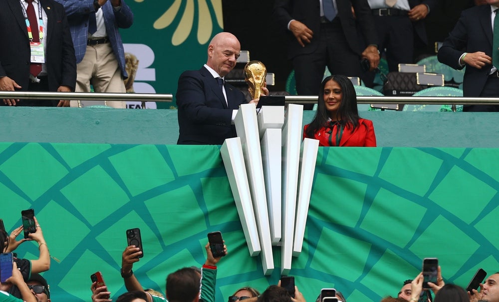  June 11, 2026; Mexico City, Mexico; FIFA President Gianni Infantino holds the FIFA World Cup trophy alongside actress and FIFA World Cup 2026 Ambassador Salma Hayek Pinault in the stand before the match.  Mandatory Credit: Kai Pfaffenbach-REUTERS 