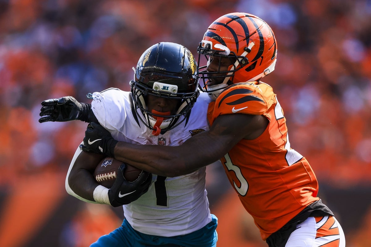 Sep 14, 2025; Cincinnati, Ohio, USA; Jacksonville Jaguars running back Travis Etienne Jr. (1) runs with the ball against Cincinnati Bengals cornerback Dax Hill (23) in the second half at Paycor Stadium. Mandatory Credit: Katie Stratman-Imagn Images