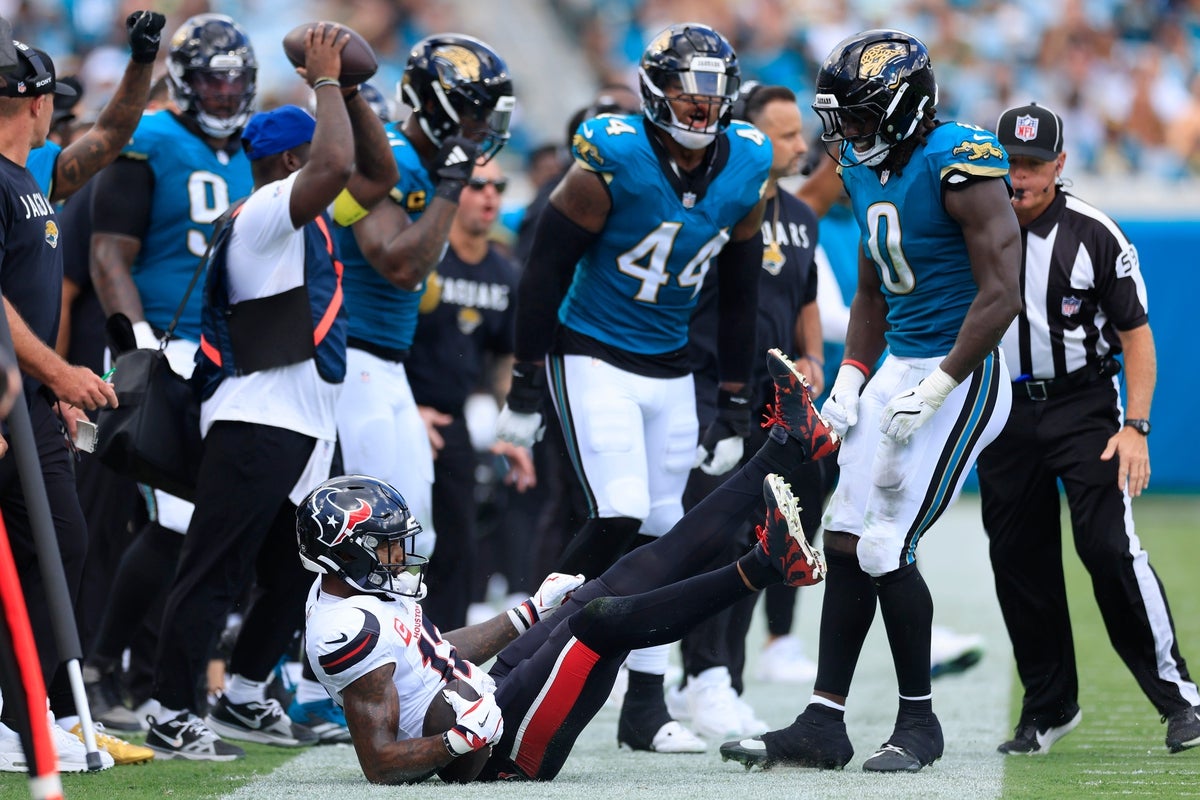 Houston Texans wide receiver Nico Collins (12) is shoved out of bounds by Jacksonville Jaguars linebacker Devin Lloyd (0) during the first quarter of an NFL football matchup at EverBank Stadium, Sunday, Sept. 21, 2025, in Jacksonville, Fla. The Jaguars defeated the Texans 17-10.